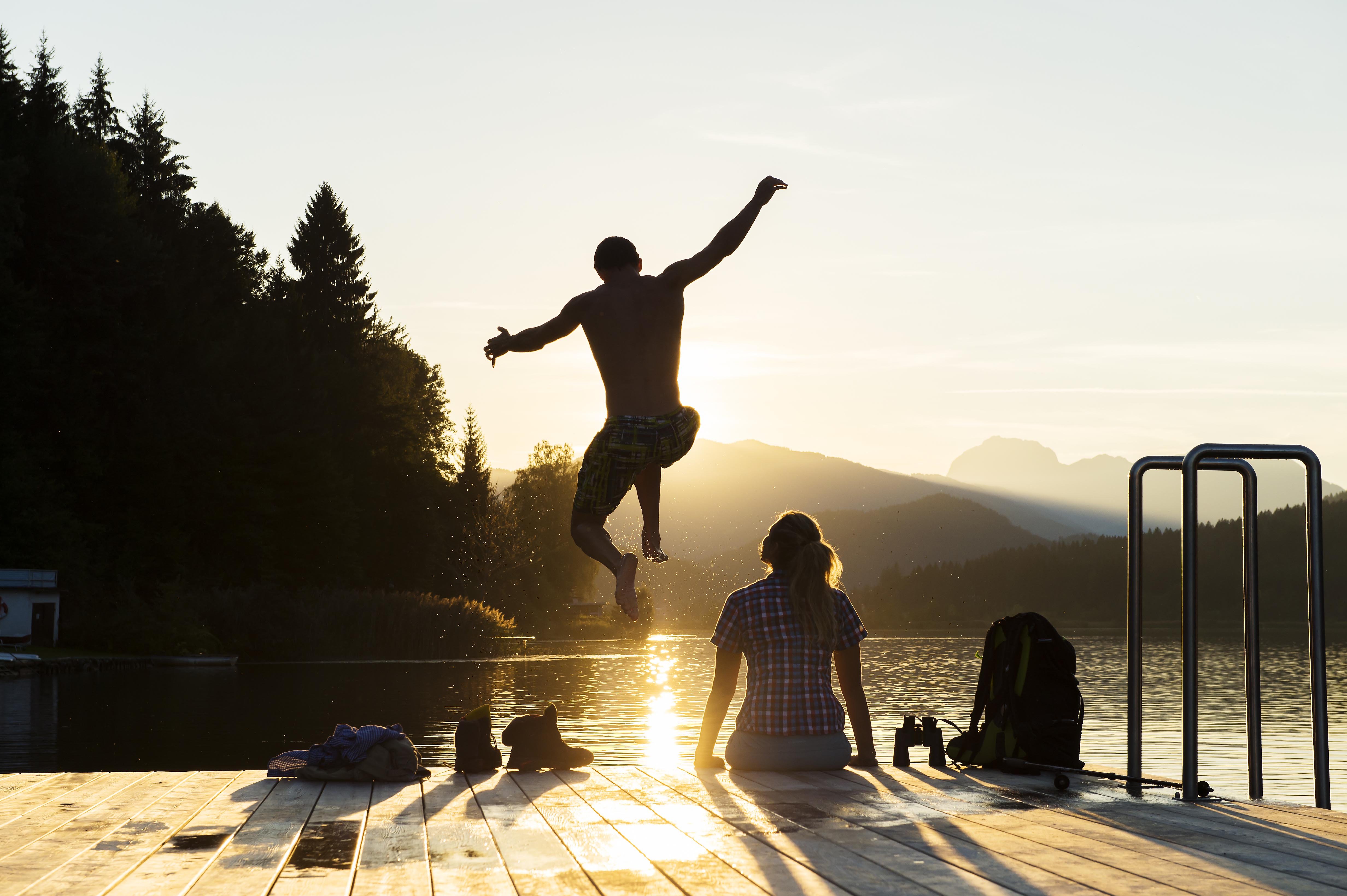Man jumping into the water from the dock at sunset