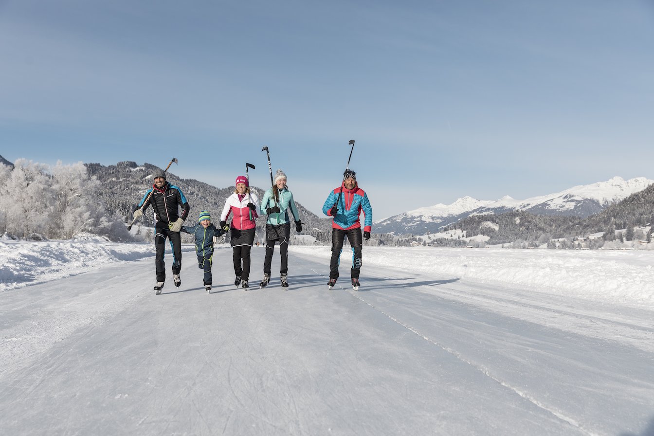 Family skating with poles on frozen surface